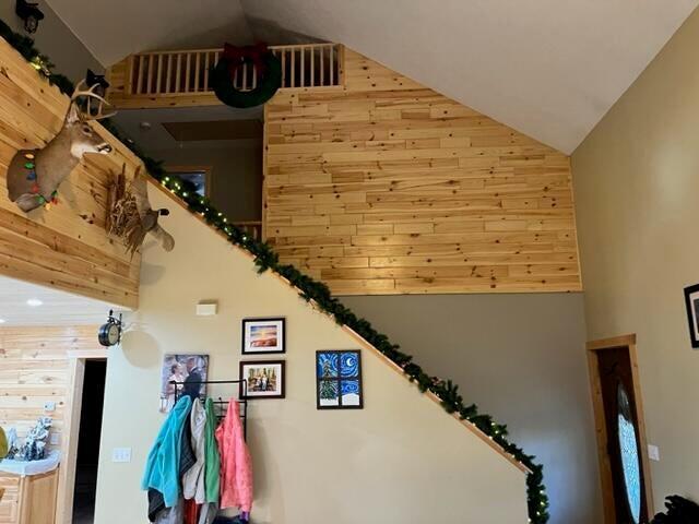 stairway with wood walls, visible vents, and high vaulted ceiling