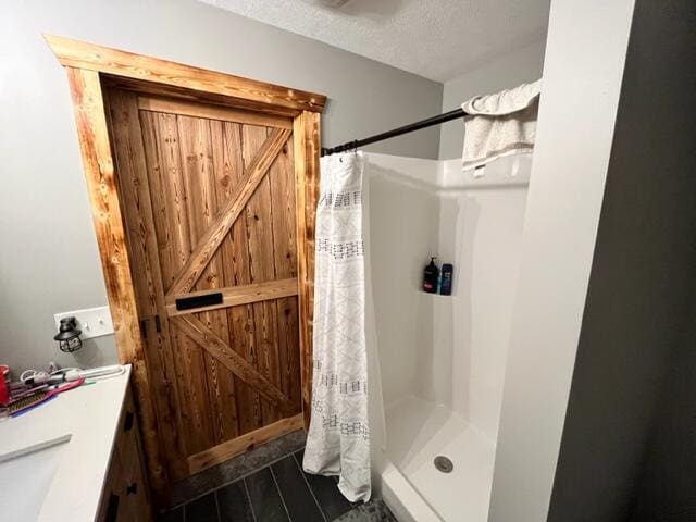 full bath with a shower with curtain, a textured ceiling, vanity, and wood finished floors