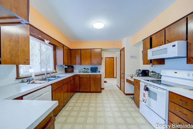 kitchen with white appliances, a sink, light countertops, brown cabinets, and light floors