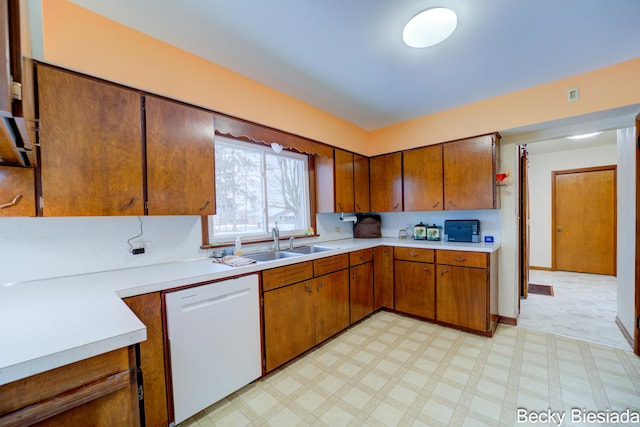 kitchen with a sink, light countertops, brown cabinets, dishwasher, and light floors