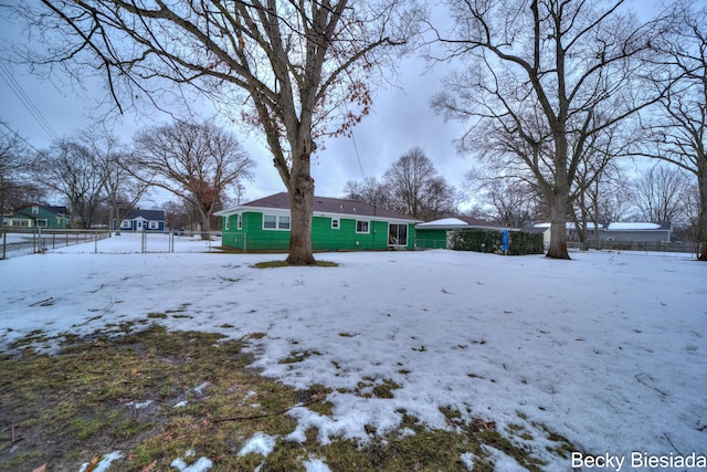 snow covered rear of property with fence