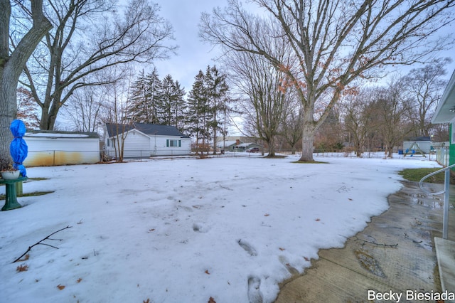 yard covered in snow with a playground and fence