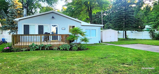 view of front facade with an outbuilding, fence, a deck, a shed, and a front lawn