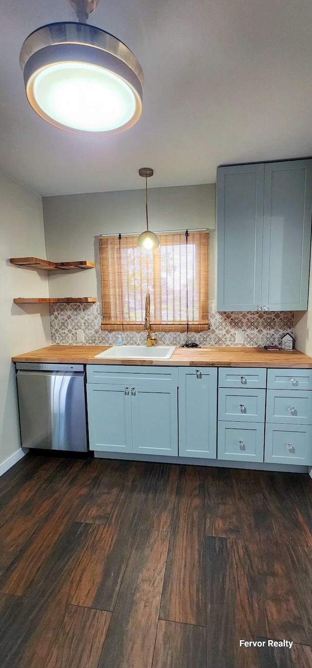 kitchen with dark wood finished floors, decorative backsplash, a sink, wooden counters, and stainless steel dishwasher