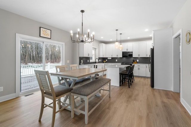 dining room featuring light wood-type flooring, a healthy amount of sunlight, visible vents, and baseboards