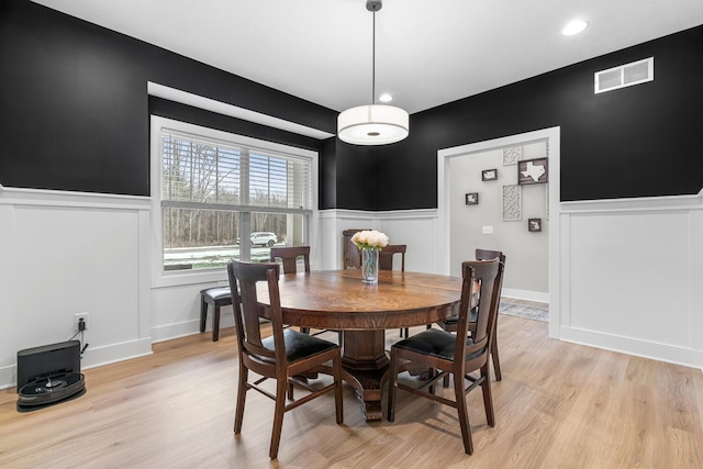 dining area featuring a wainscoted wall, light wood-style flooring, and visible vents