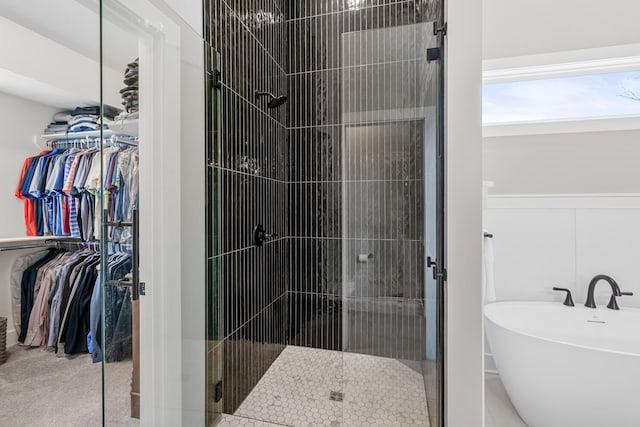 bathroom featuring a stall shower, a walk in closet, and a freestanding tub