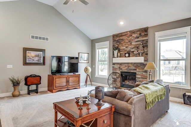 living room with plenty of natural light, visible vents, light colored carpet, and a stone fireplace