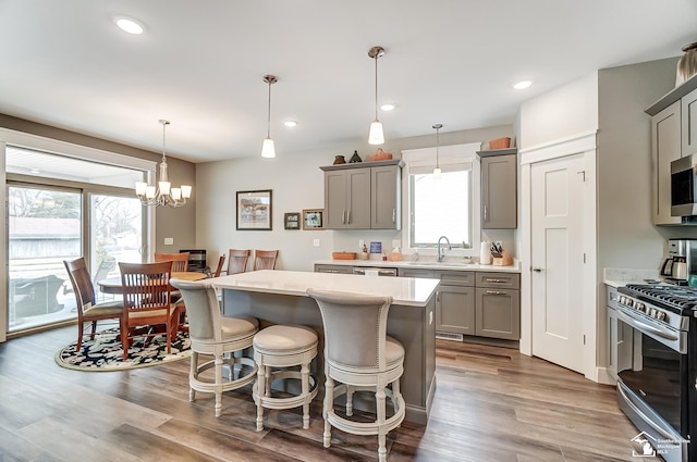 kitchen with appliances with stainless steel finishes, light countertops, wood finished floors, and gray cabinetry