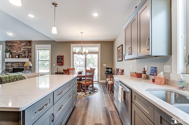 kitchen featuring a fireplace, dark wood finished floors, stainless steel dishwasher, and gray cabinetry