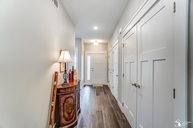 entryway with dark wood finished floors, visible vents, and baseboards