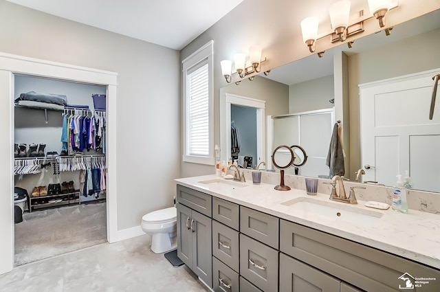 bathroom with double vanity, a stall shower, toilet, and a sink