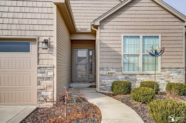 property entrance featuring an attached garage and stone siding