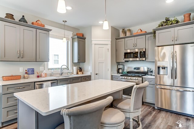 kitchen with a breakfast bar area, appliances with stainless steel finishes, gray cabinets, and a sink