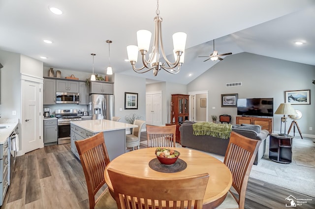 dining area featuring recessed lighting, visible vents, dark wood-style floors, vaulted ceiling, and ceiling fan with notable chandelier