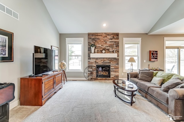 carpeted living area featuring plenty of natural light, visible vents, baseboards, and a stone fireplace