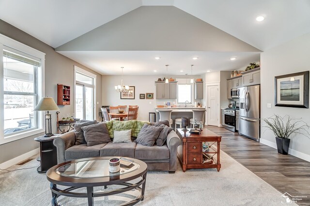 living area with baseboards, a chandelier, wood finished floors, high vaulted ceiling, and recessed lighting