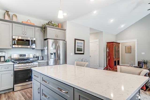 kitchen with lofted ceiling, appliances with stainless steel finishes, gray cabinets, a center island, and light wood finished floors