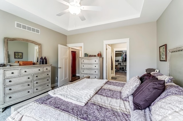 bedroom with visible vents, a raised ceiling, ceiling fan, a walk in closet, and a closet