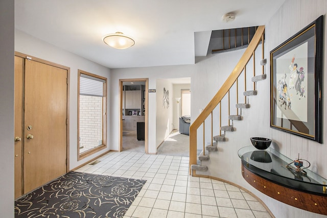 foyer with light tile patterned floors, stairway, and baseboards