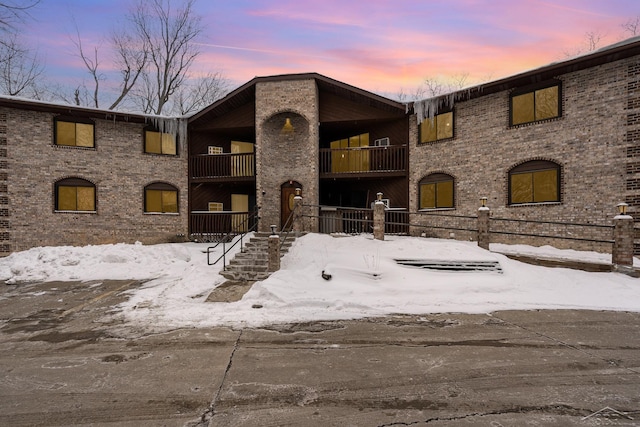 view of front of house featuring brick siding and a balcony