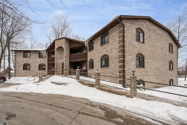 view of front of property with brick siding, fence, and a balcony