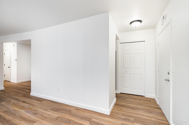 interior space featuring baseboards and light wood finished floors