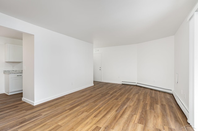 spare room featuring baseboard heating, light wood-type flooring, a baseboard radiator, and baseboards