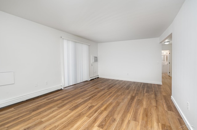 empty room featuring a baseboard radiator, light wood-style flooring, baseboards, and baseboard heating