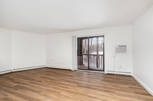 unfurnished room featuring a wall unit AC, a baseboard radiator, and wood finished floors