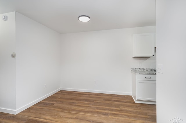 unfurnished dining area with baseboards and wood finished floors