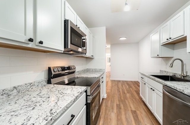 kitchen featuring white cabinets, light wood-style flooring, stainless steel appliances, and a sink