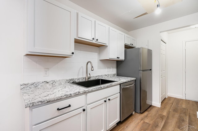 kitchen featuring a sink, white cabinetry, light wood-style floors, appliances with stainless steel finishes, and decorative backsplash