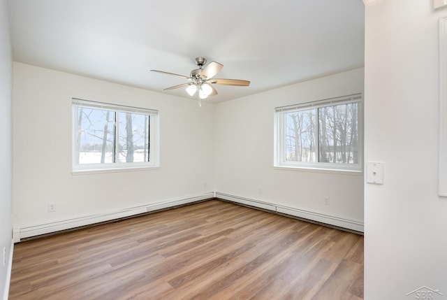 empty room with a ceiling fan, a wealth of natural light, a baseboard heating unit, and wood finished floors