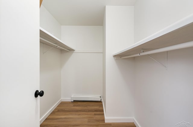 spacious closet with a baseboard radiator and wood finished floors