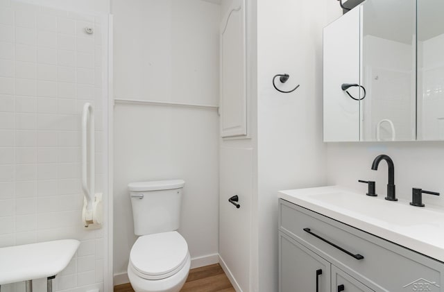 full bath with toilet, baseboards, wood finished floors, and vanity