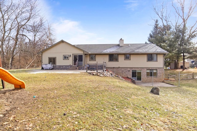 rear view of property featuring a patio, a playground, a yard, brick siding, and a chimney