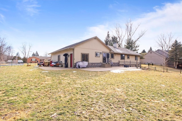 rear view of house featuring fence, entry steps, a chimney, a yard, and a patio