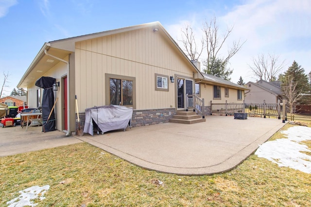 back of house featuring stone siding, fence, and a patio area