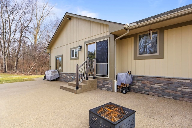 exterior space with a patio, a fire pit, and stone siding