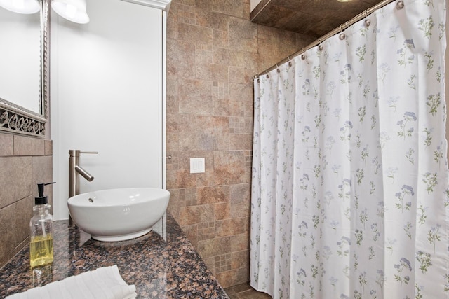 full bath with tile walls, a shower with shower curtain, and a sink