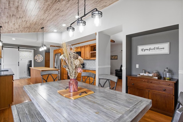 dining area with light wood finished floors, recessed lighting, vaulted ceiling, a barn door, and wooden ceiling