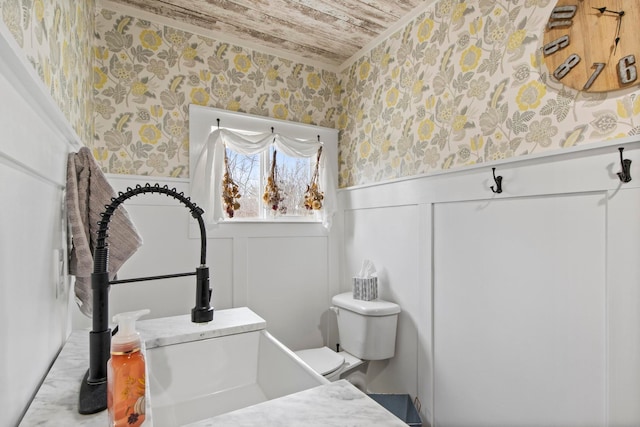 bathroom featuring wallpapered walls, wooden ceiling, toilet, and wainscoting