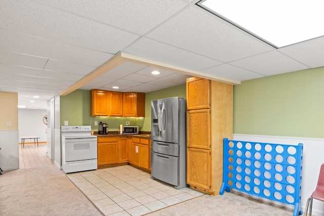 kitchen with light tile patterned floors, stainless steel appliances, light colored carpet, and wainscoting