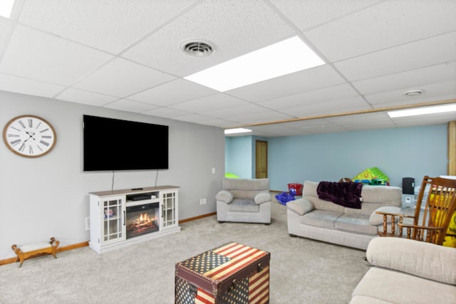 carpeted living area featuring visible vents, a paneled ceiling, baseboards, and a glass covered fireplace