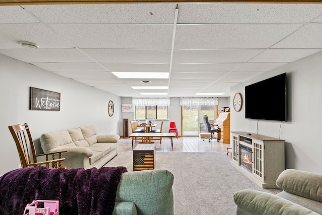 living area with a paneled ceiling and a glass covered fireplace