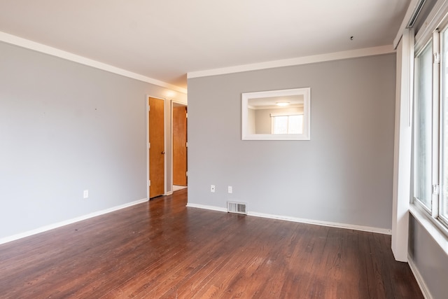 empty room with dark wood-style flooring, visible vents, and baseboards