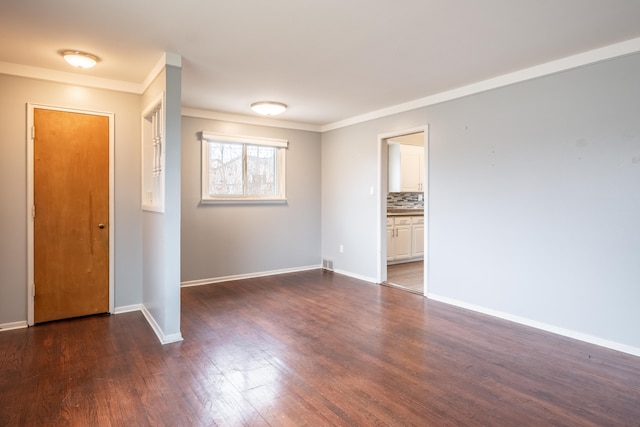 unfurnished room featuring ornamental molding, dark wood-style flooring, visible vents, and baseboards