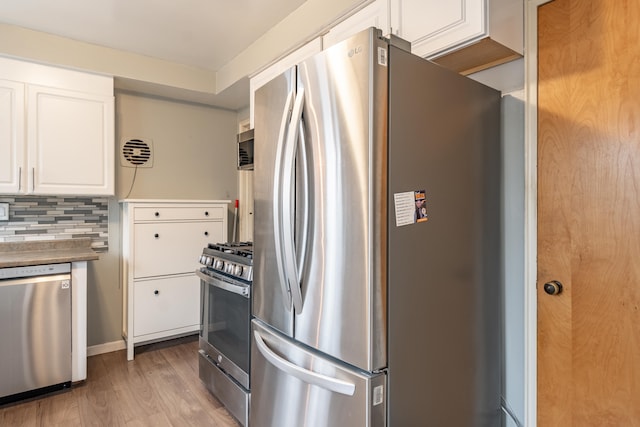 kitchen featuring stainless steel appliances, white cabinets, light wood-style flooring, and backsplash