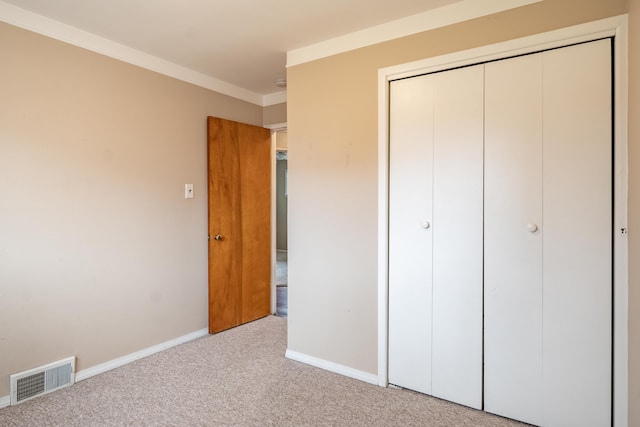 unfurnished bedroom featuring visible vents, baseboards, ornamental molding, a closet, and carpet